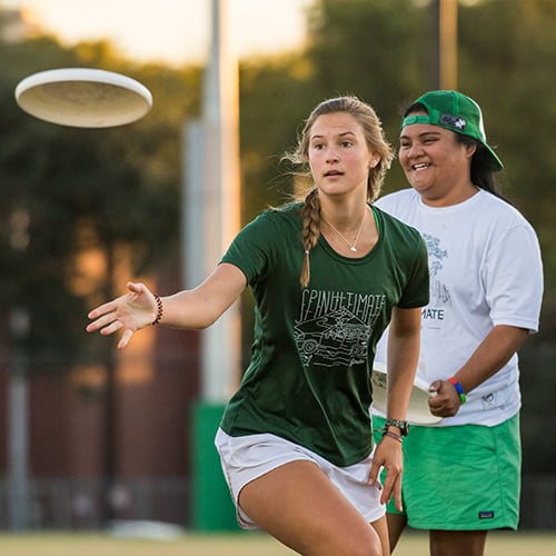 Two students playing frisbee.