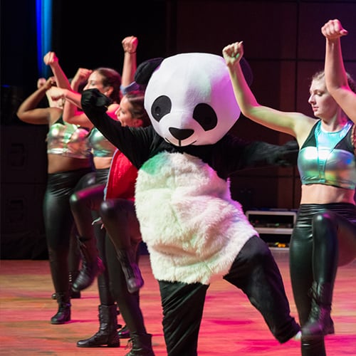 Femail students performing with person dressed in a panda suit.