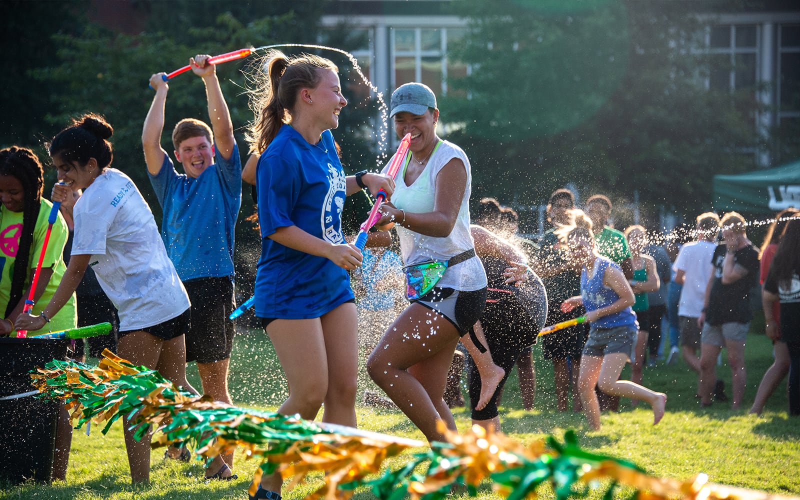 Students having water fight on campus green.