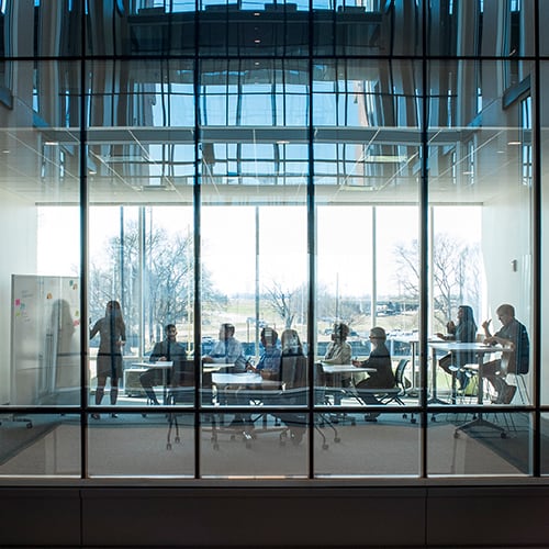 Professor and students in modern classroom with double sided glass.