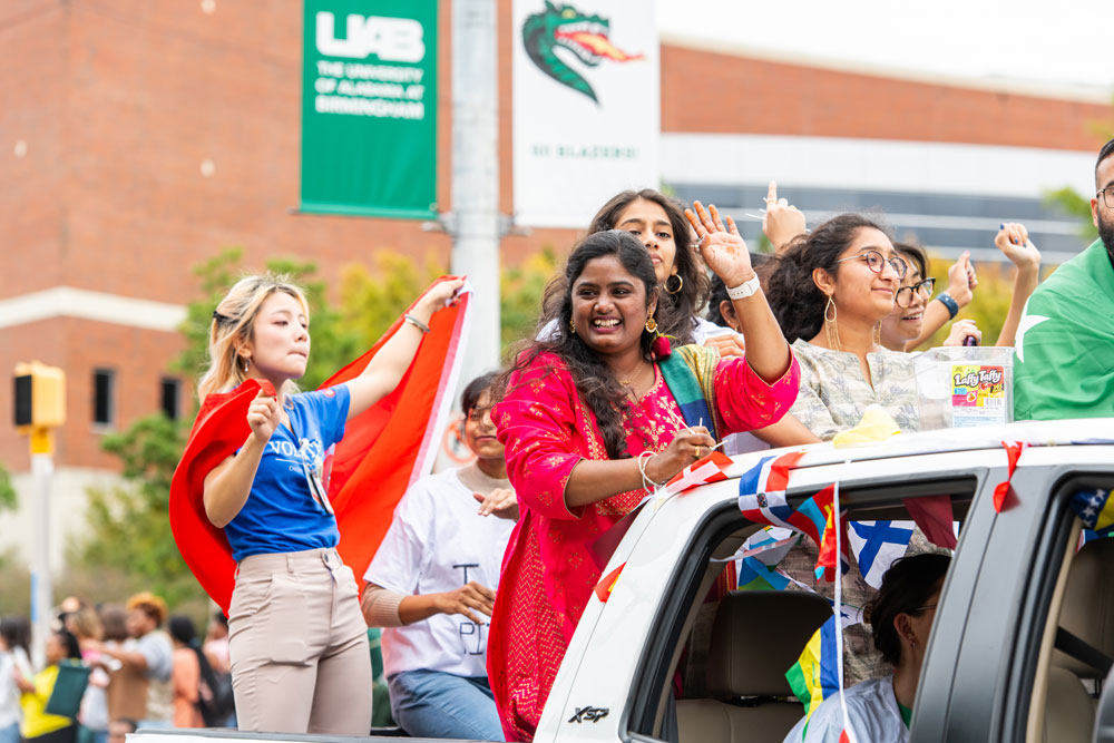 Smiling and dancing INTO UAB Students ride a truck at homecoming. 