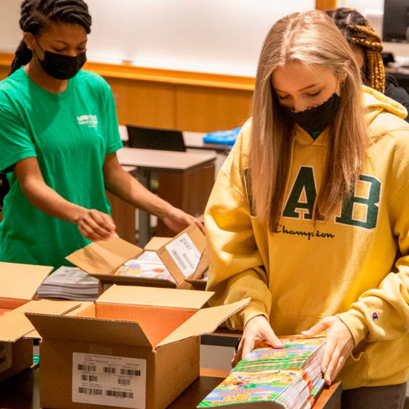 Two students in facemasks sorting donated supplies. 