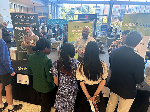 A group of students talk to a Tech Expo vendor