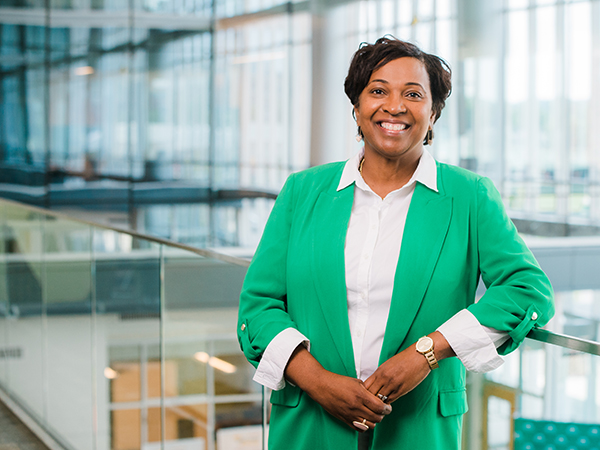 Woman with short dark hair smiling, wearing a green jacket 