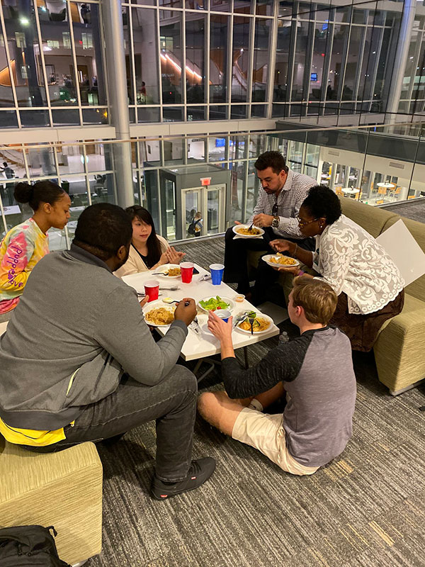 Students sitting around a table with food. 