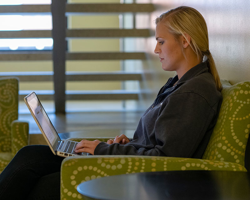 Woman sitting in chair with laptop.