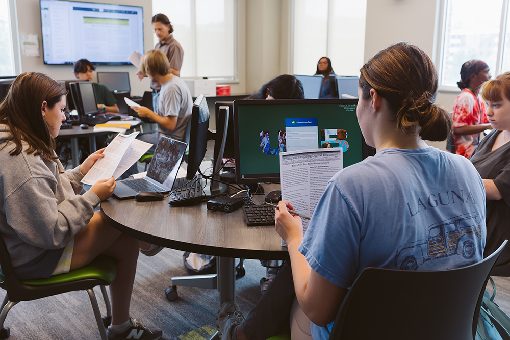 Dr. Bacha's class reviews their print materials in a computer lab