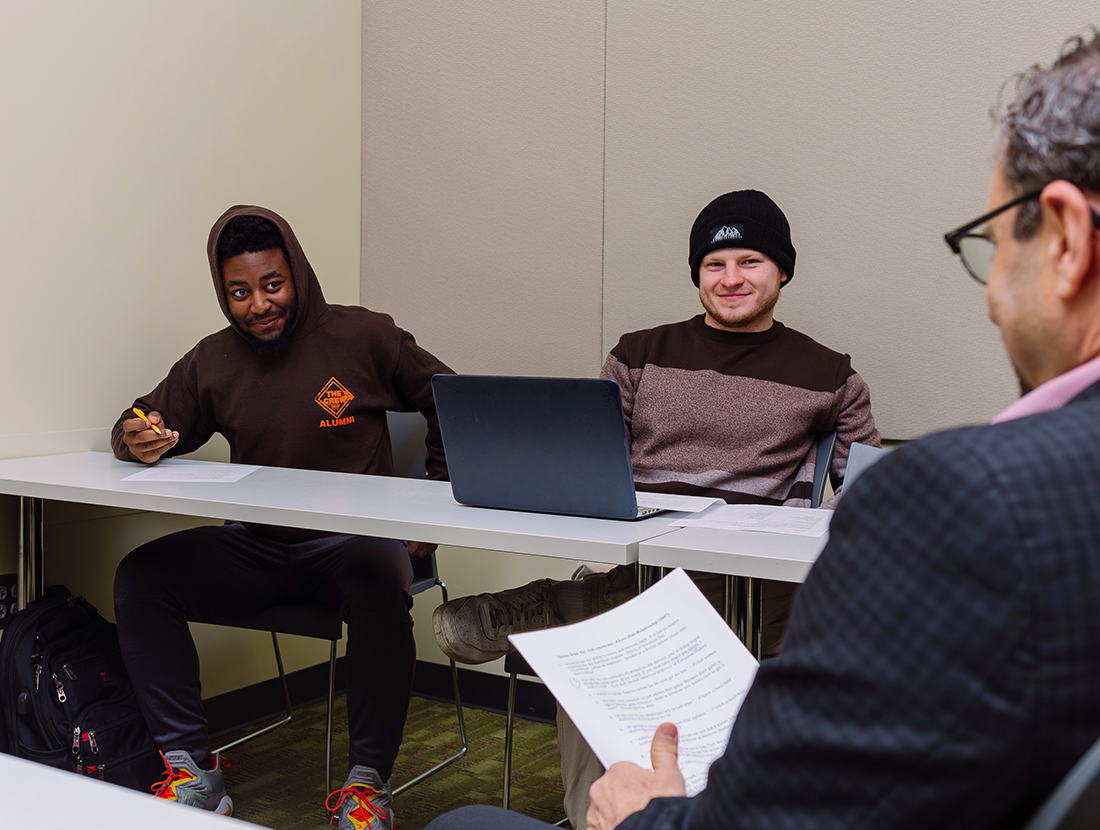 "Two students listen to Dr. Jonathan Wiesen talk"