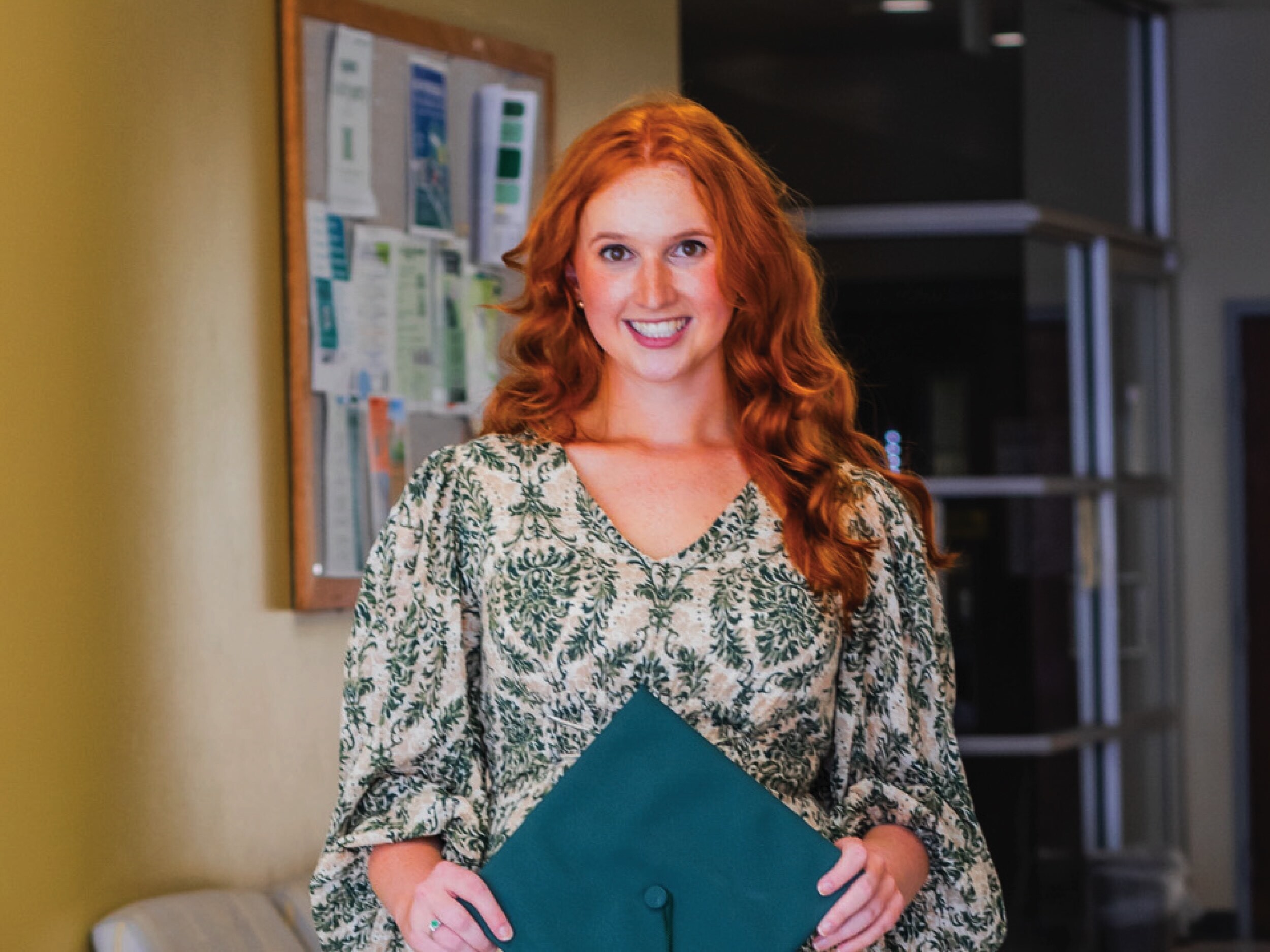Kate Flowers holds her graduation cap in the Chemistry building