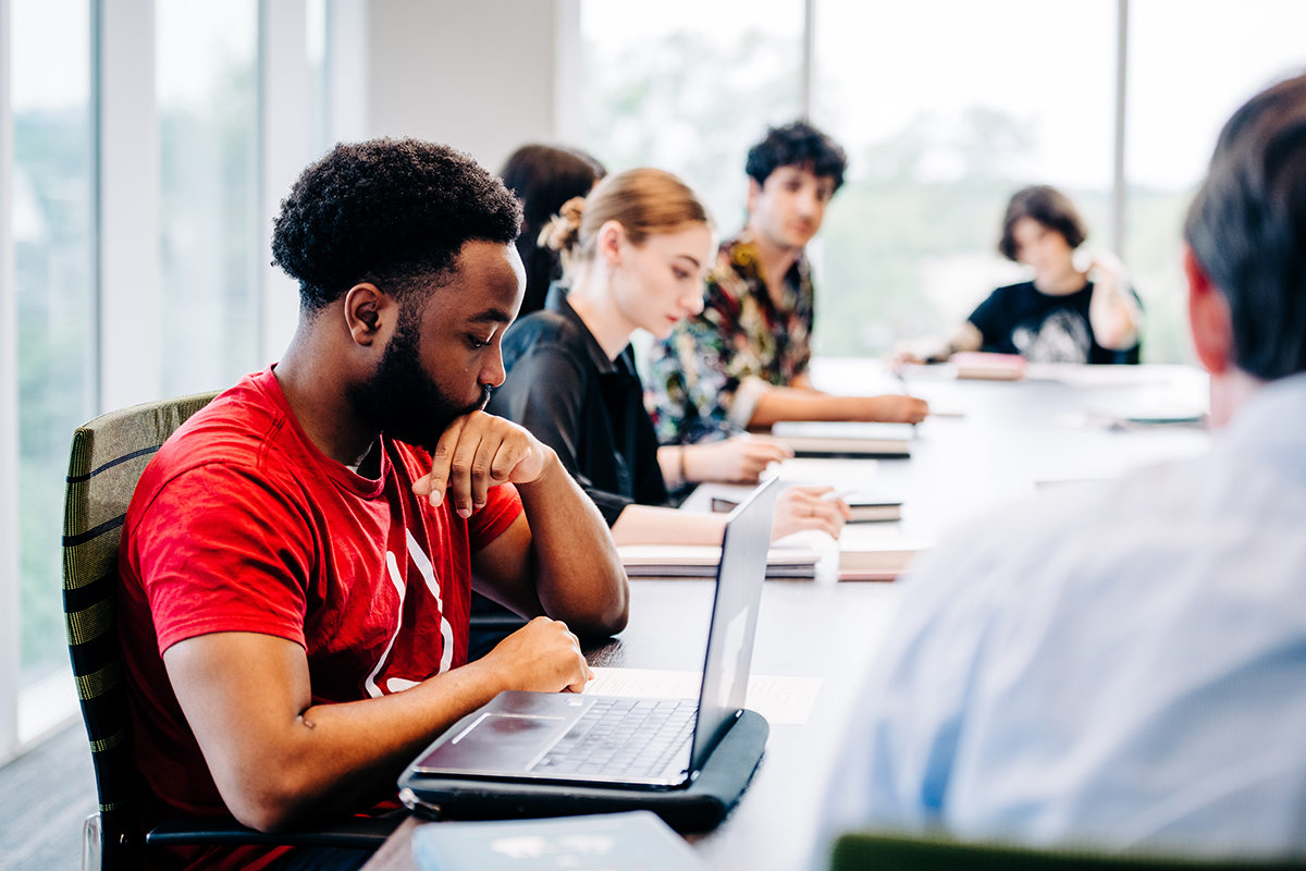 Students are sitting at long table in philosophy class being taught by Dr. Joshua May, PhD (Associate Professor, Philosophy) in a conference room classroom in University Hall, September 2022.