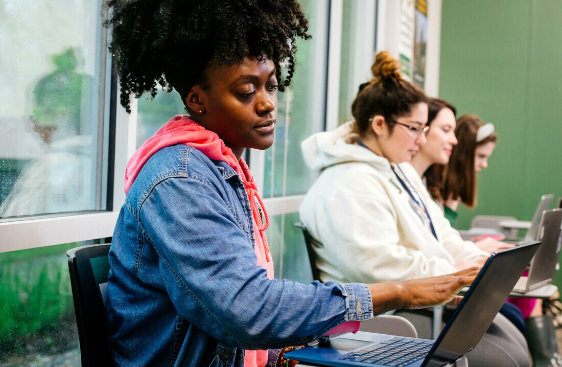 From side, several students are sitting at desks in a Social Work 120 Class in the ROTC Building, April 2022.