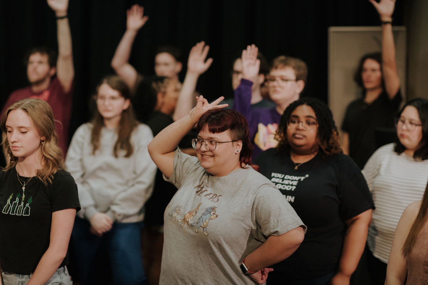 Sopranos and altos rehearsing, some with hands raised.