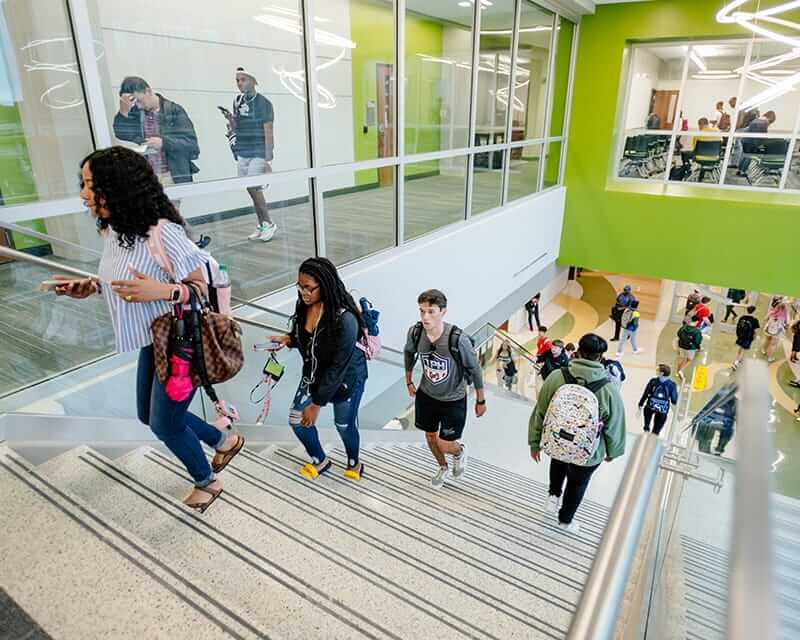 Student walking up the stairs in the Hill Student Center. 