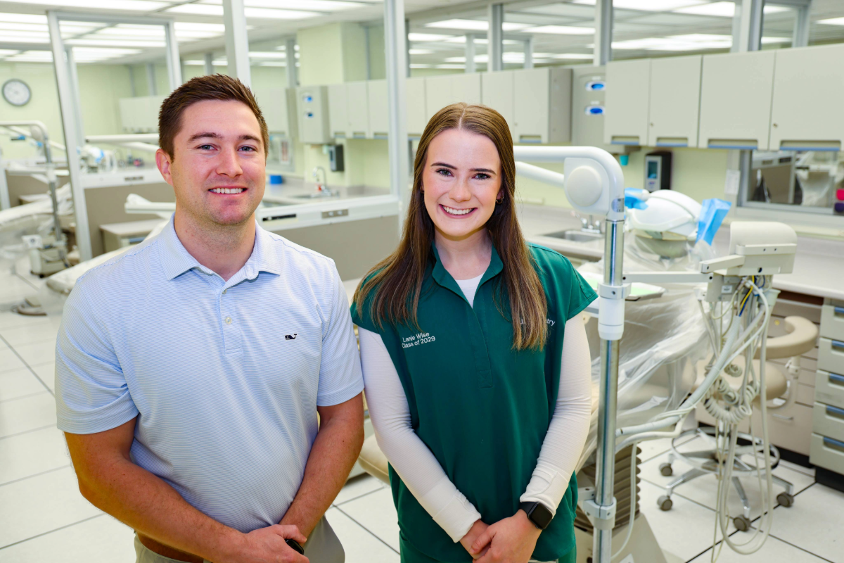 White girl with brown hair (Lanie Wise) smiling and standing next to white man (Dr. Teeples) smiling who is wearing a white polo. They are standing in a dental clinic.
