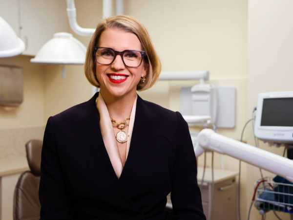 Blonde woman in professional attire smiling in clinical setting