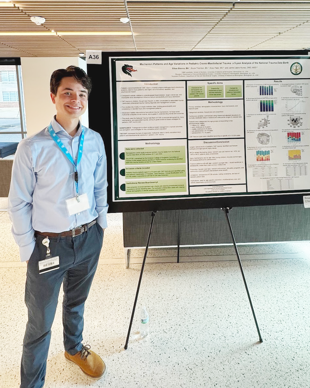 Ethan Brenna (white male in blue button up and slacks) smiling while presenting their research poster on pediatric craniofacial trauma at SEMSS 2025.
