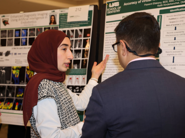 Dental student presenting research poster to faculty member at UAB SOD Scholars Symposium