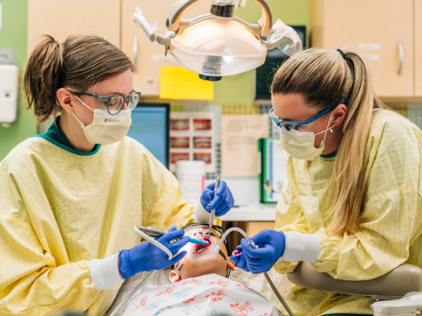 Two dental students proving dental care to a child at Give Kids A Smile event