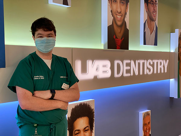 Austin Stiles wearing surgical mask and standing in front of UAB Dentistry sign.