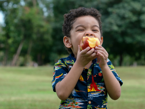adobe stock image of kid eating an apple outdoors