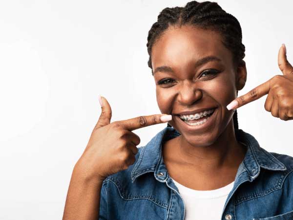 Girl smiling pointing at her braces