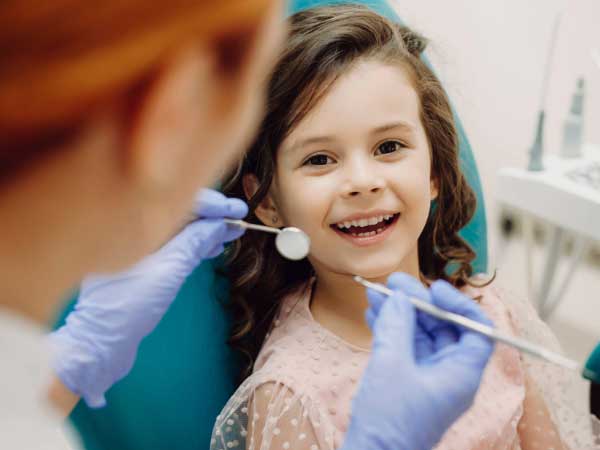 Little girl smiling in dental chair with dentist