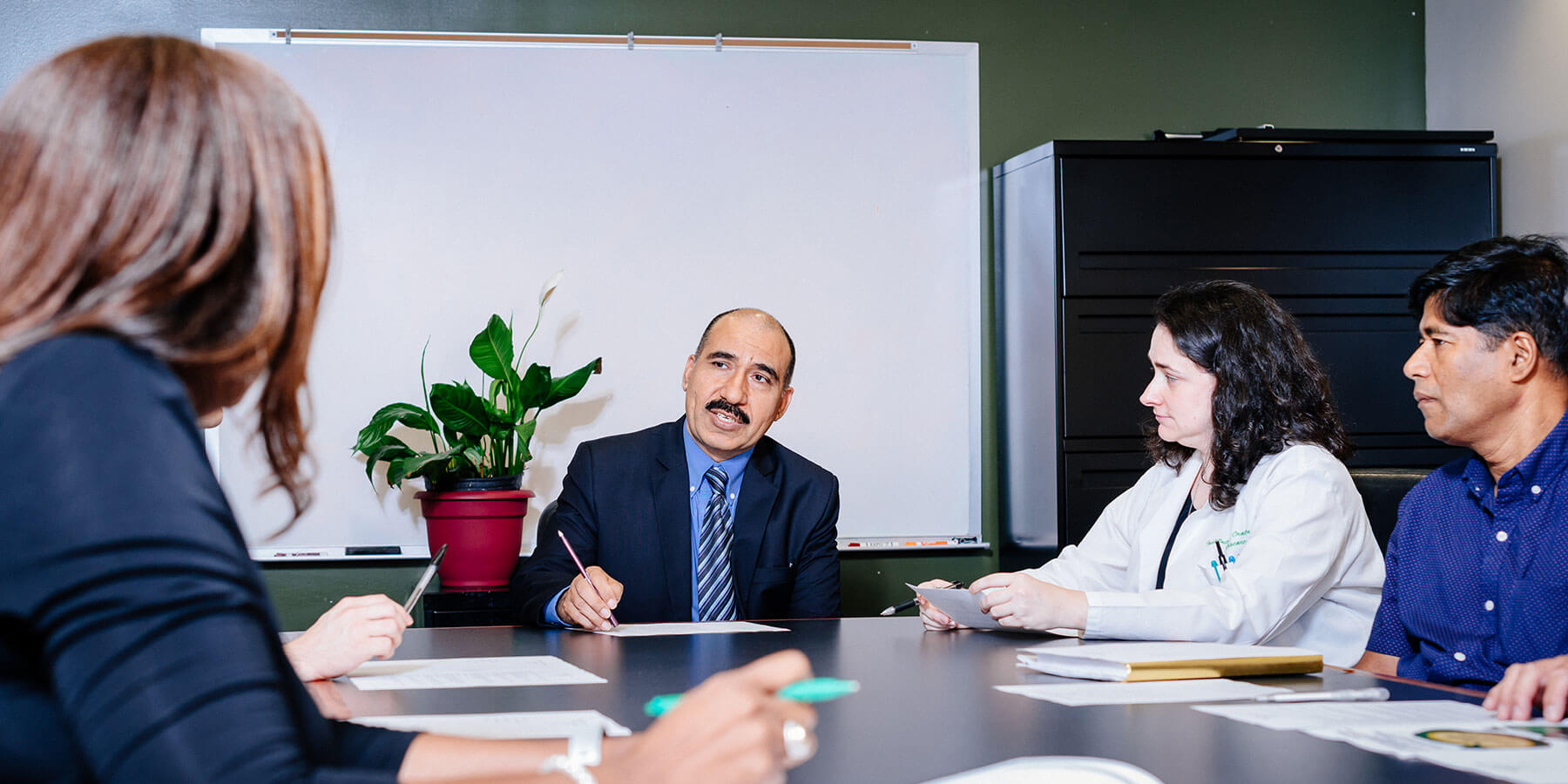 Faculty of the School of Dentistry discussing matters at a conference table. 