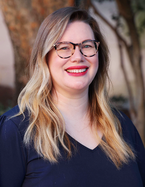 Woman with glasses and red lipstick smiling for photo outdoors