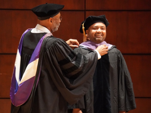 Bobby Patel hooded by Dr. Bradford and Dr. Wadiak at the 2024 D.M.D. Commencement Ceremony