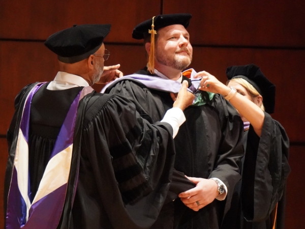 Dave Verhine hooded by Dr. Bradford and Dr. Wadiak at the 2024 D.M.D. Commencement Ceremony