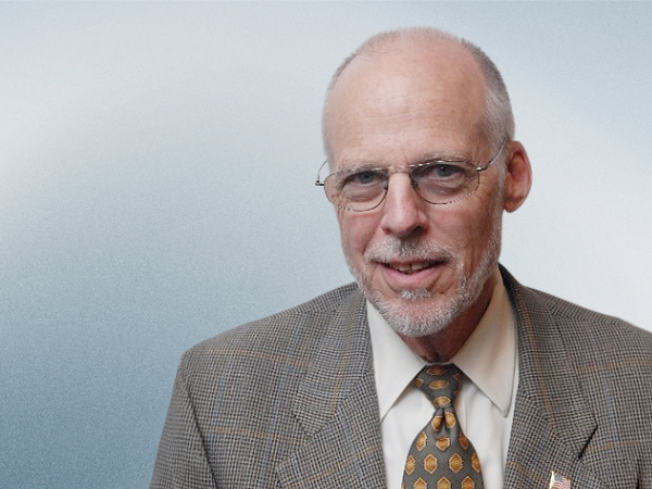 Dr. Palcanis smiling against blue grey background