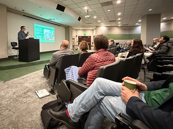 man speaking at front of auditorium