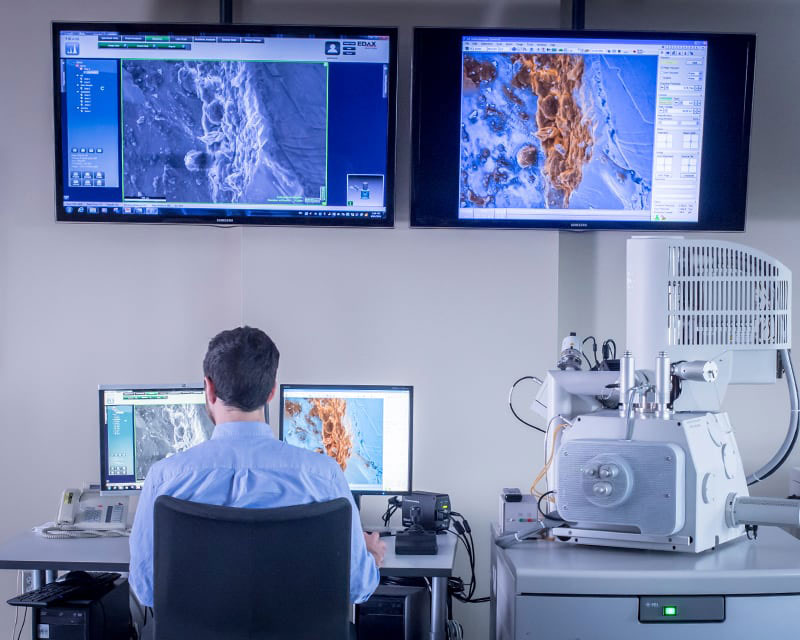 Man sitting in front of four monitors.