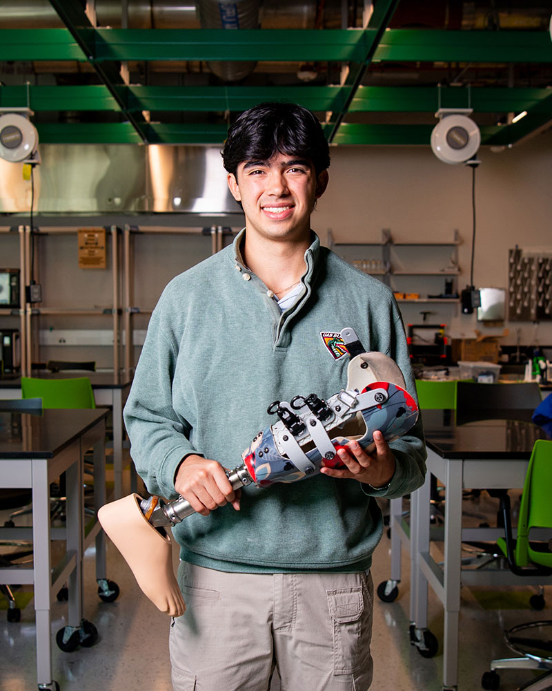 Male student holds a prosthesis in the engineering design lab.
