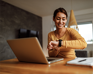Woman sitting at her computer looks at her watch