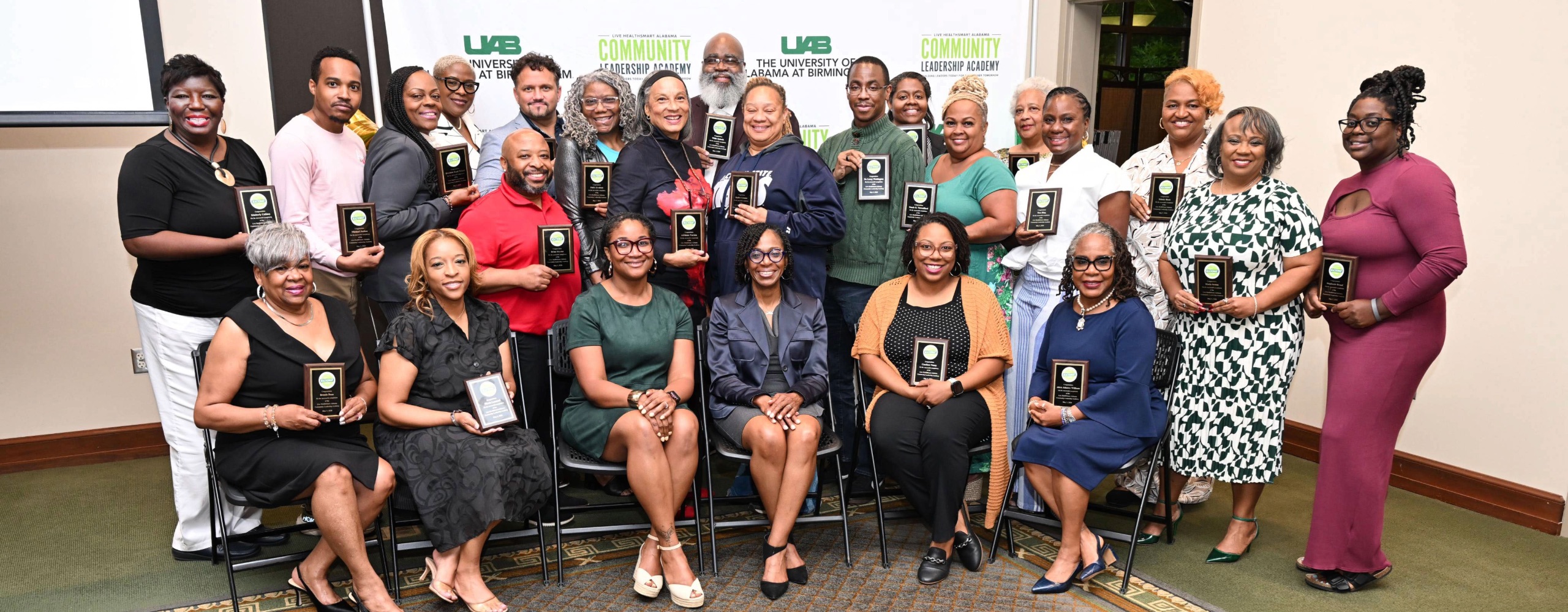 Group photo of people holding plaques marking their completion of the community leadership academy.