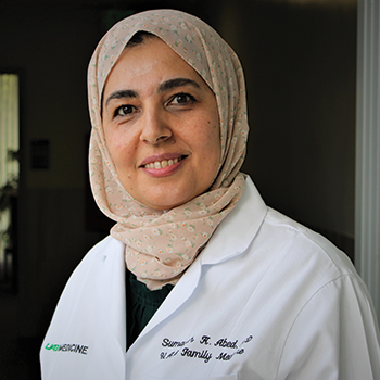 sumayah abed smiles while wearing a white coat