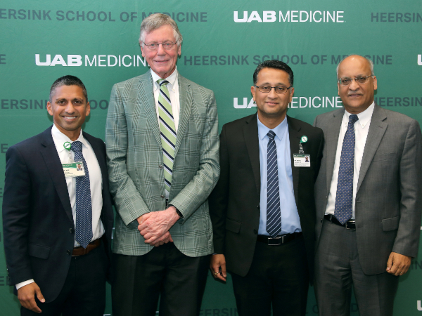 Four men stand in front of a green Heersink UAB School of Medicine backdrop