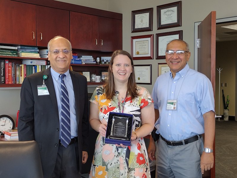 Anna Hurst, M.D., accepting the 2023 Brewer-Heslin Award standing with Heersink School of Medicine Dean Anupum Agarwal, M.D, and Anindya Dutta, Ph.D., professor and chair of the UAB Heersink School of Medicine Department of Genetics