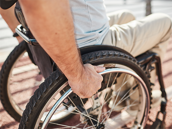Man pushes his wheelchair on an accessible outdoor path.