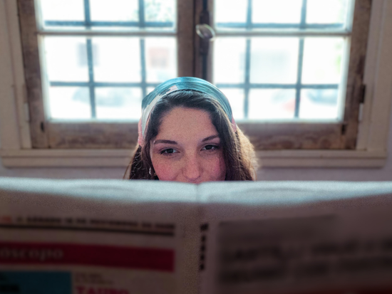 woman reading newspaper in front of window