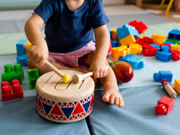 Toddler playing with blocks and wooden drum