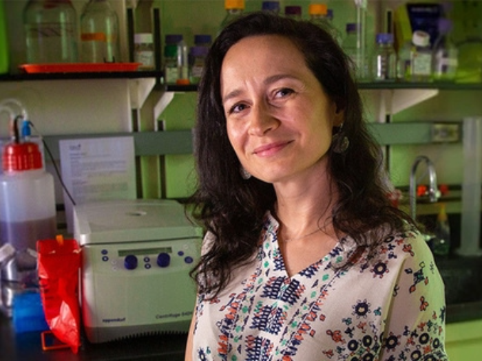 Ksenia Matlawska-Wasowska, Ph.D., stands in front of lab equipment.