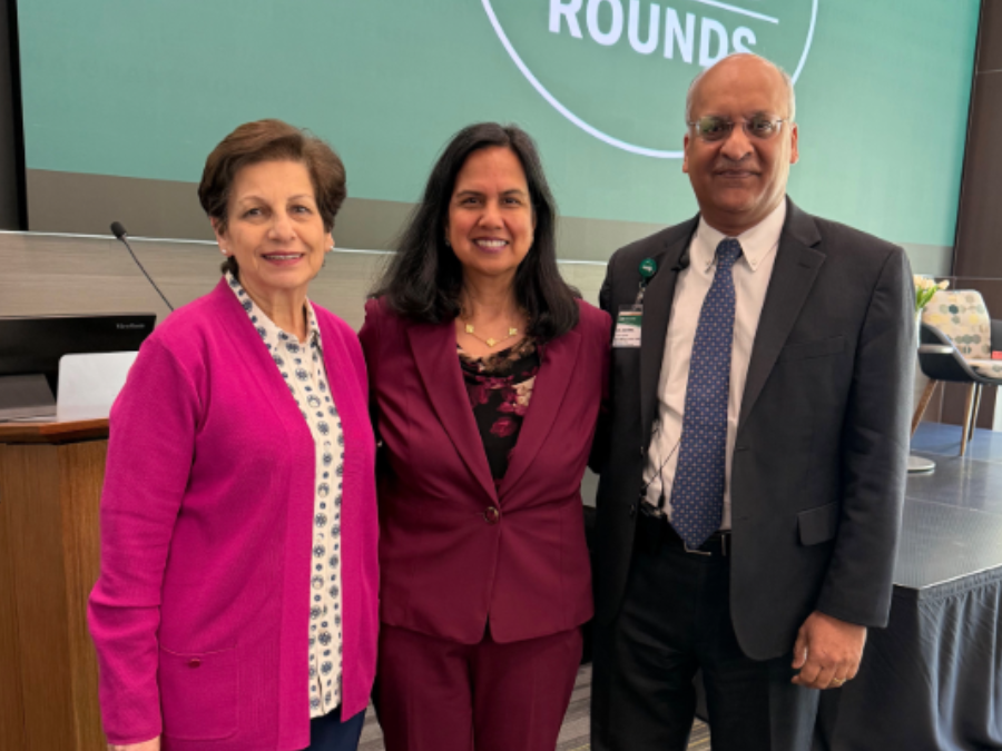 Mona, Fouad, M.D., MPH, Sharmila Makhija, M.D., MBA, and Anupam Agarwal, M.D., stand in front of a large green graphic behind them displays 