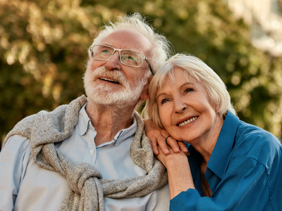 Older couple sits together in a park looking off into the distance