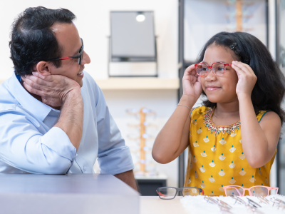 Father and daughter try on glasses at an optical shop
