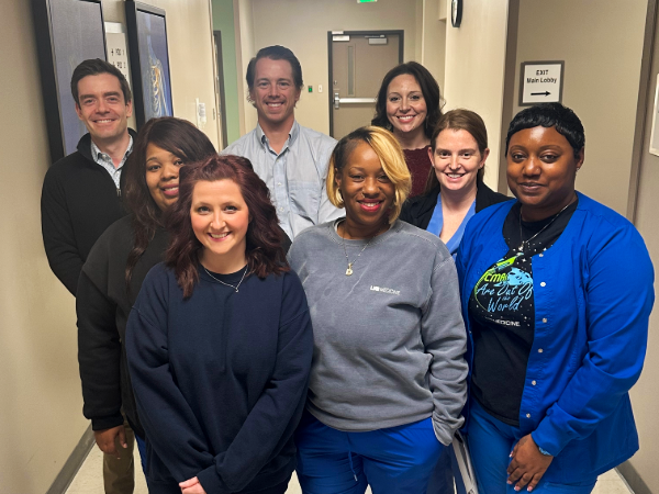The UAB Orthopaedics joint team stands together in a hallway, posing for a group photo in casual professional attire