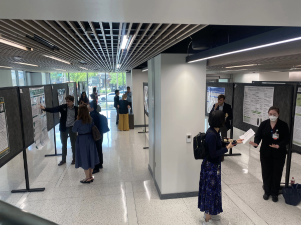 Attendees review and discuss research posters in a hallway poster session.