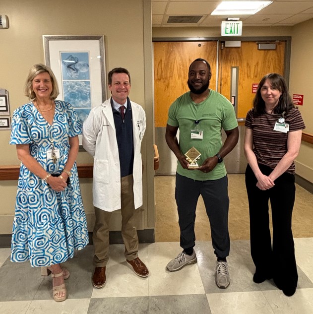 Four people standing in a hallway with the champion of safety, Jonathan Dodson, holding a plaque