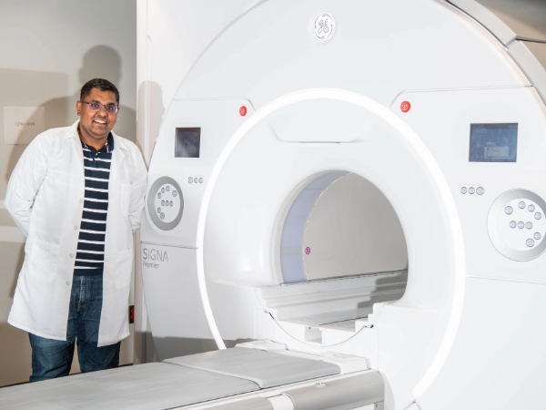 Dr. Virendra Mishra, PhD (Associate Professor, Radiology is standing next to GE Healthcare SIGNA Premier 3T Wide-Bore MRI scanner at UAB Highlands, October 2024.
